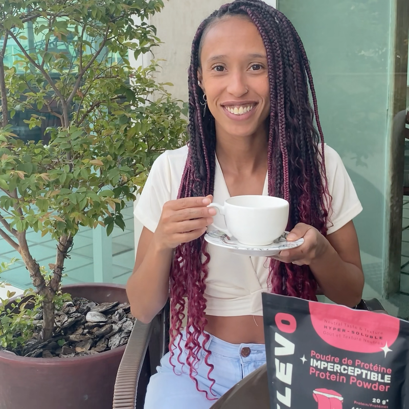 Woman holding a cup of coffee with ELEVO Nutrition protein powder package