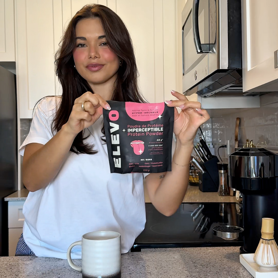 Woman holding a package of ELEVO Nutrition protein powder in the kitchen.